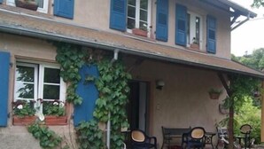 A two-story house with a covered porch, outdoor seating, and bicycles. - Pension Linstant (Le Hohwald)