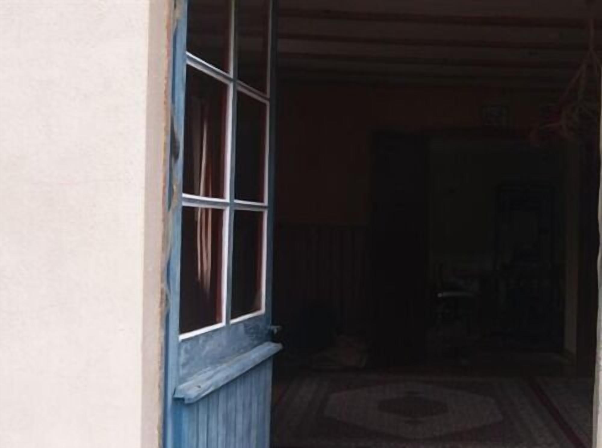 Una habitación con puerta de madera y ventana con cortinas.