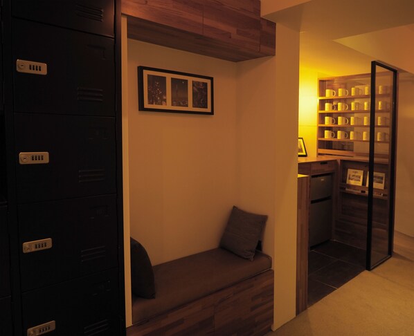 A room with a built-in bench, a wall-mounted shelf with mugs, and a framed picture above the bench.