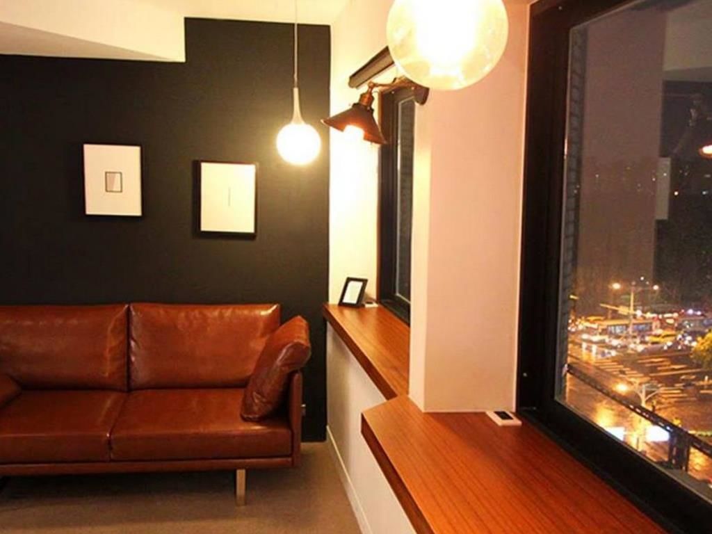 A modern living room with a leather sofa, a wooden bench, and a large window overlooking a cityscape at night.