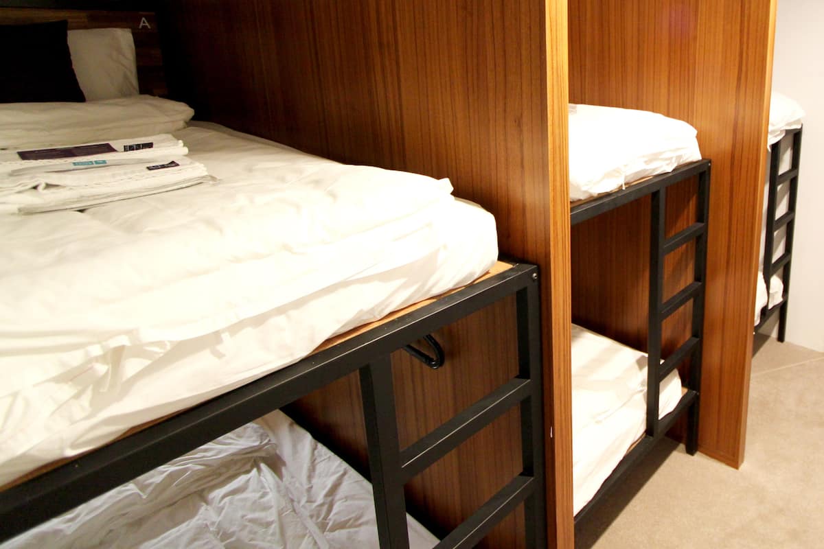 Dormitorio con literas, paredes de madera y estructura metálica negra.