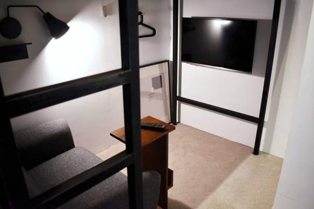Una habitación con una cama, un escritorio, un televisor y una lámpara.