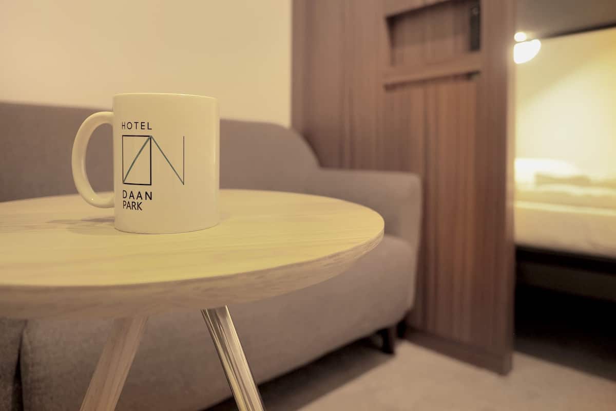 Una taza blanca con la leyenda 'HOTEL DAAN PARK' sobre una pequeña mesa redonda.