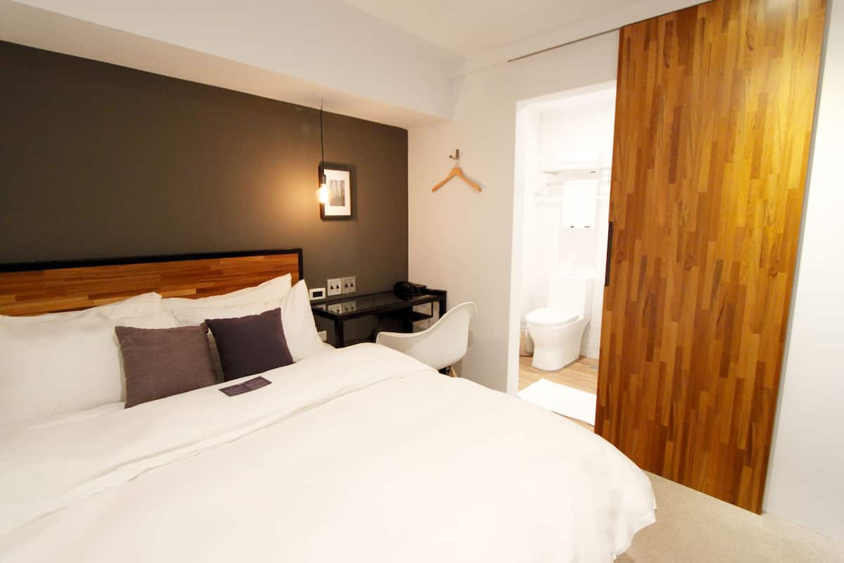 Una habitación de hotel moderna con una cama grande, un escritorio y un armario de madera.