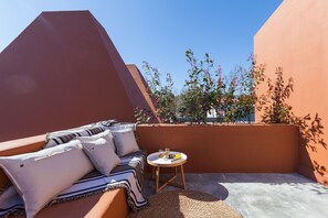 Relax in a tranquil outdoor space with a cushioned sofa, striped blanket, and woven rug.