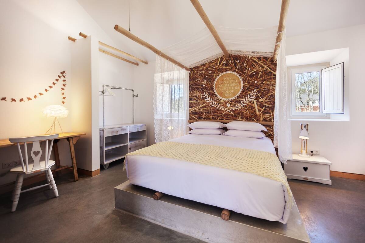 A bedroom with a bed, bedside table, lamp, and a wall with a circular design.