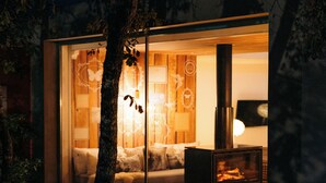 A modern, glass-walled interior with a cozy seating area, a fireplace, and a small table.
