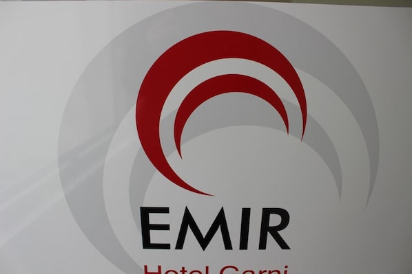 A logo with the word "EMIR" and "Hotel Corni" below it. - Hotel Garni Emir (Cologne)