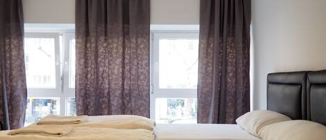 Habitación de hotel con dos camas, cabeceros y una ventana con cortinas.