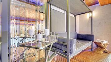 Una habitación moderna con separador de vidrio, cama con dosel y suelo de madera.