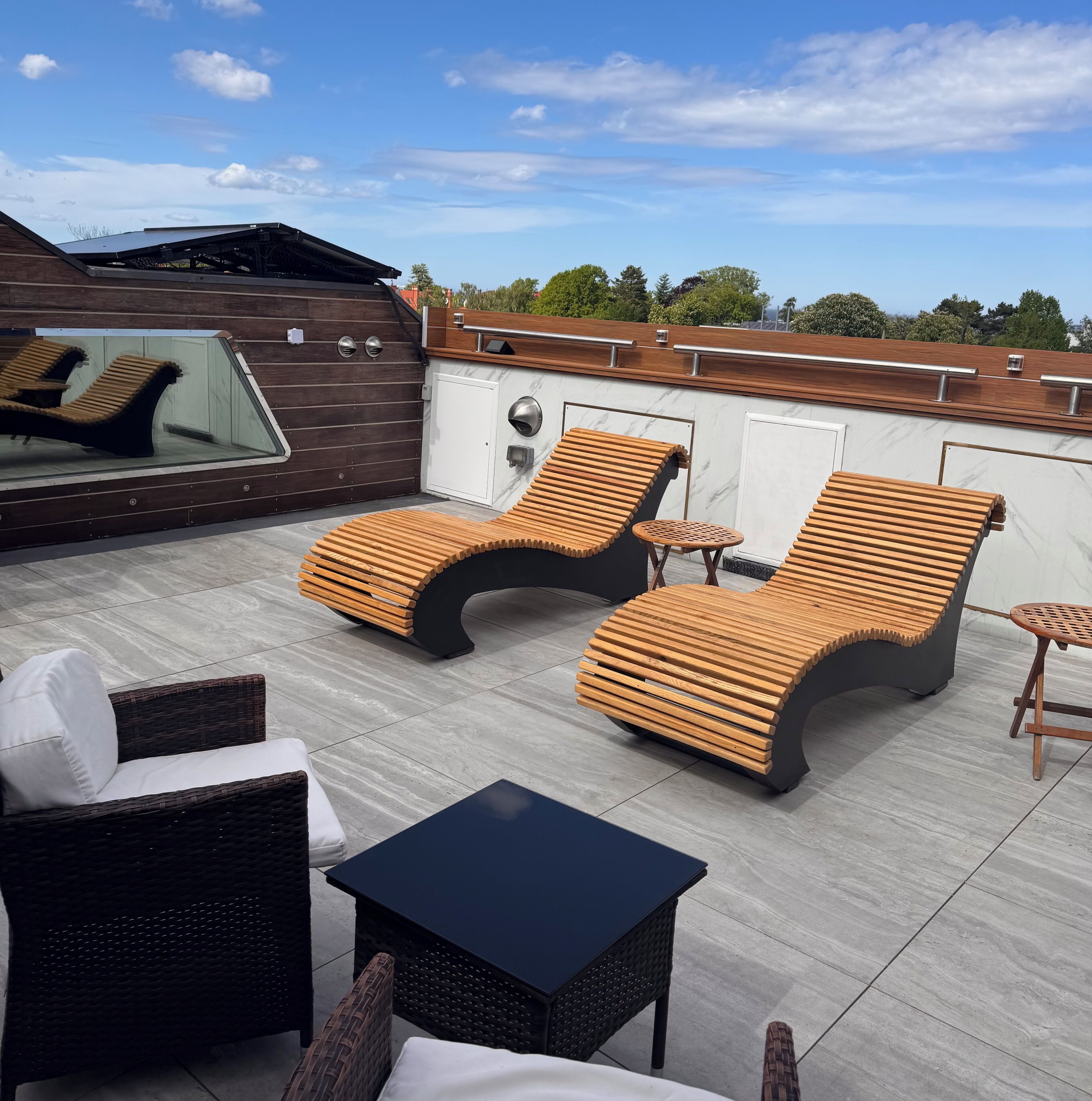 Una terraza en la azotea con dos sillones de descanso, una mesita y un sofá de mimbre.