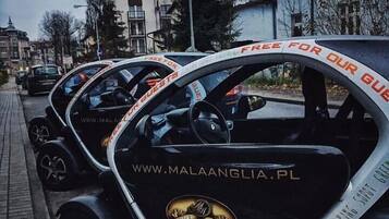 Una fila de coches negros estacionados en una calle con pegatinas que dicen 'FREE FOR OUR GUESTS'.