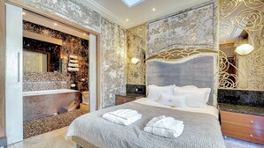 Un dormitorio amplio con una cama grande, un baño independiente y un muro decorativo.