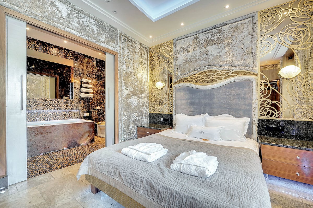 Ein geräumiges Schlafzimmer mit einem großen Bett, einem separaten Badezimmer und einer dekorativen Wand.