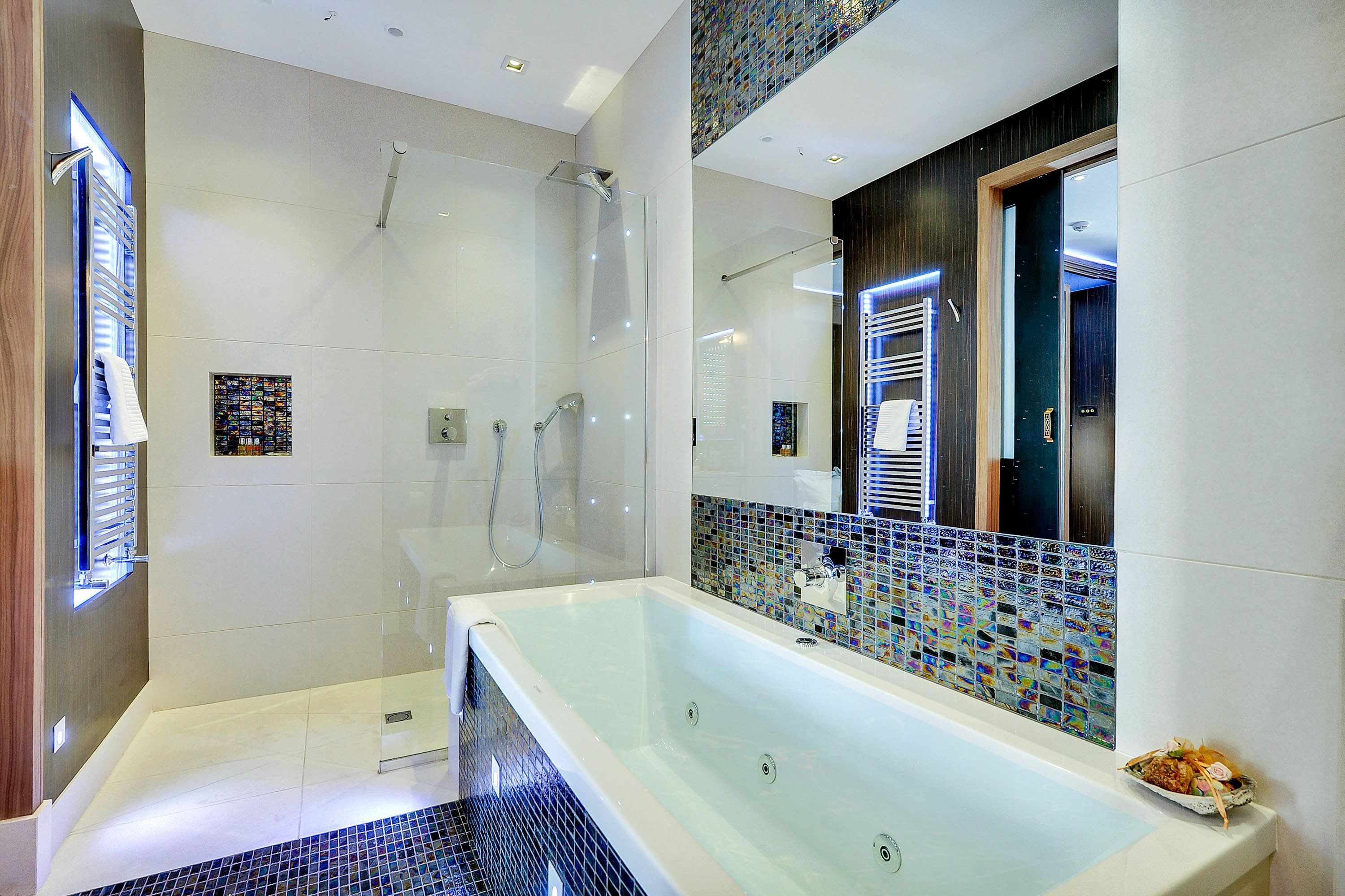 A modern bathroom with a glass-enclosed shower, a large bathtub, and a tiled backsplash.