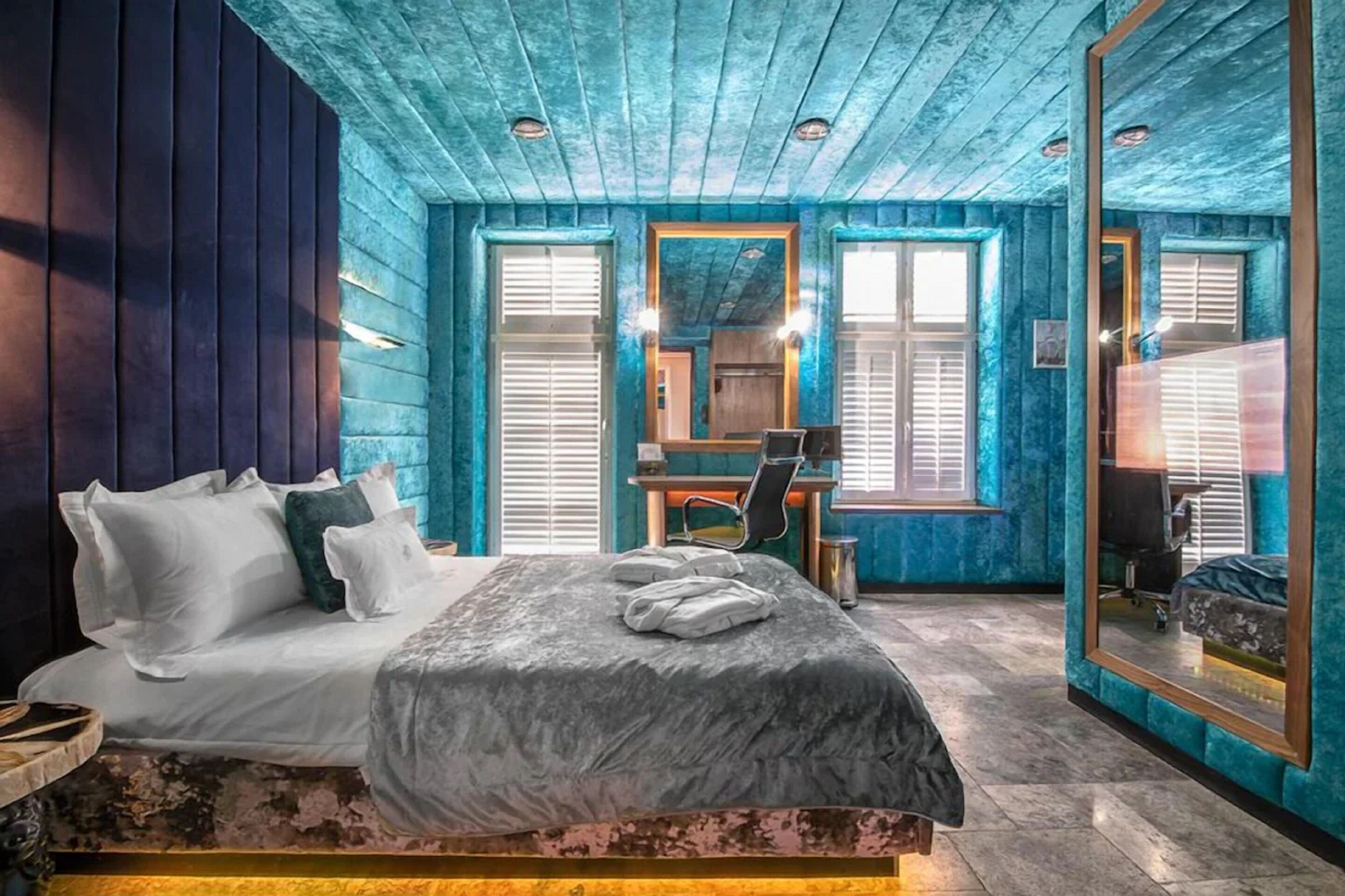 Un dormitorio con cama, escritorio y espejo.