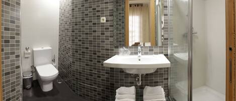 A modern bathroom with a white toilet, a sink with a mirror above it, and a glass shower enclosure.