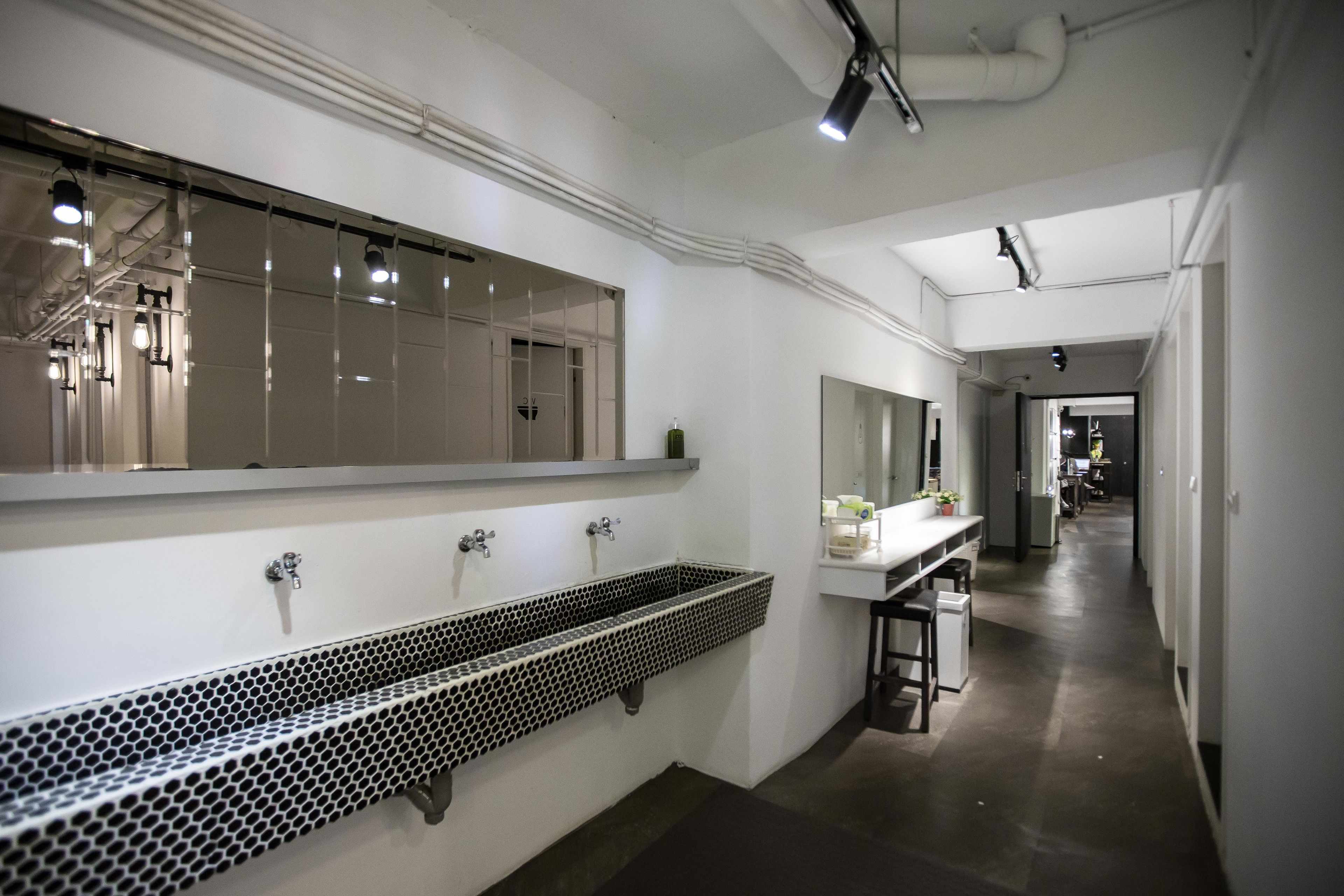 A modern bathroom with a large mirror, a black and white sink, and a countertop with a plant.