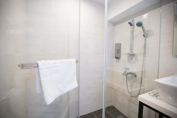 A modern bathroom with a glass shower enclosure, a white sink, and a towel rack. - We Come Hostel (Taipei)