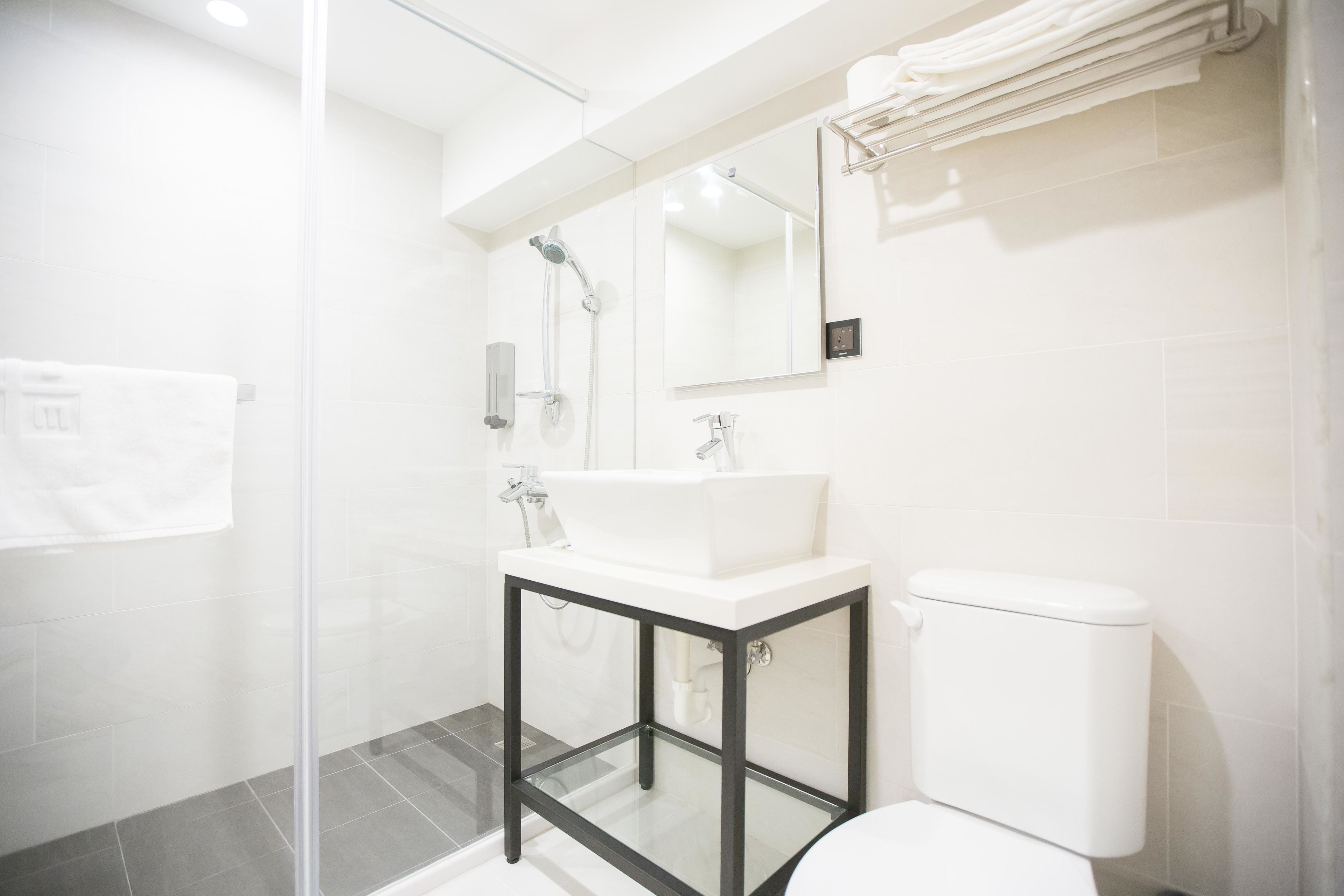 A modern bathroom with a glass shower enclosure, a white sink, and a toilet.