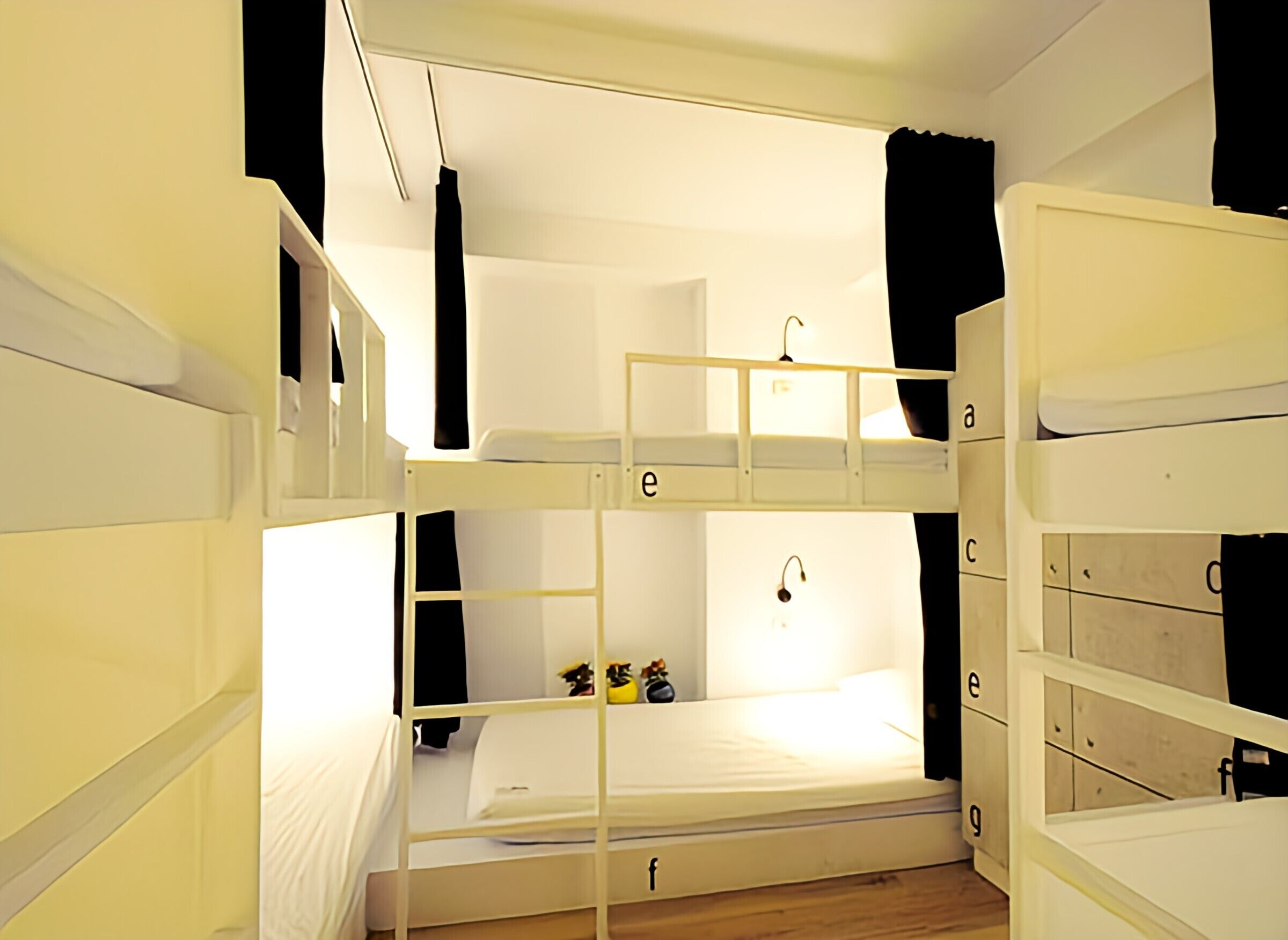 A bunk bed room with a white color scheme, a hanging light fixture, and a small toy on the lower bunk.