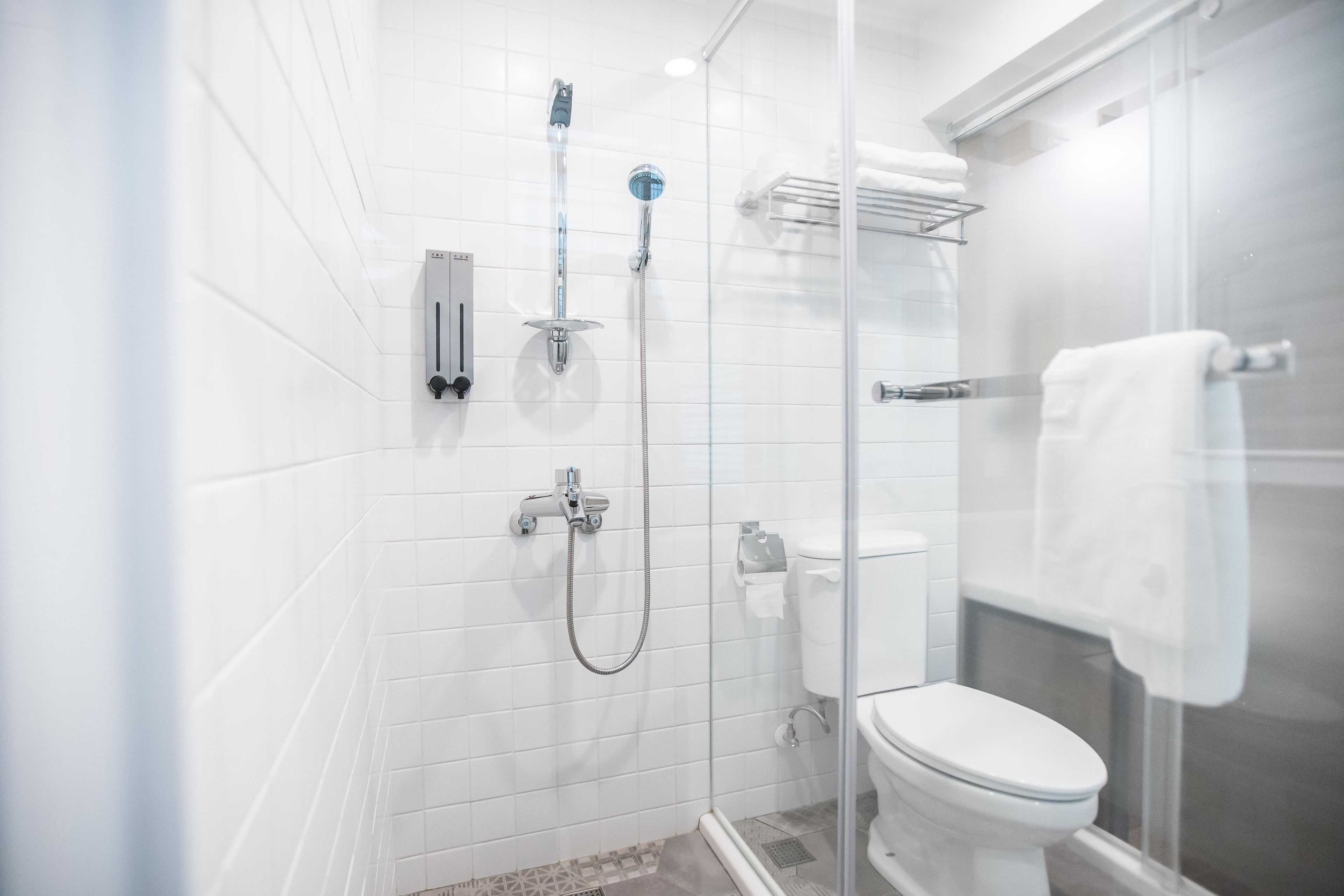 A modern bathroom with a glass-enclosed shower, a toilet, and a towel rack.