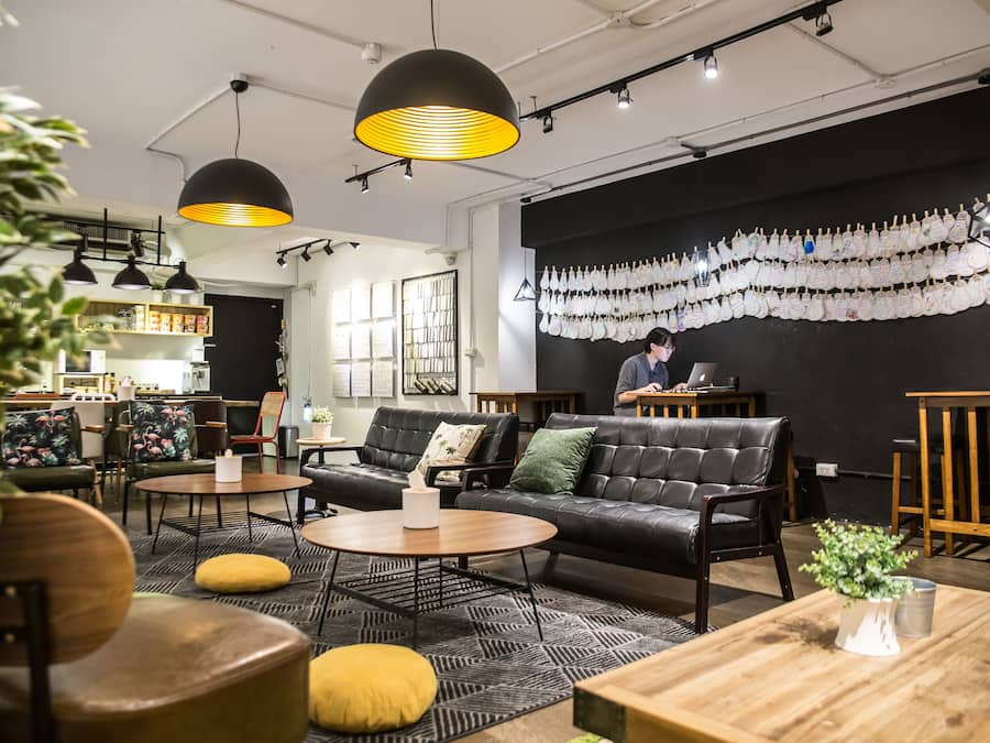 A modern interior with a black leather sofa, wooden tables, and pendant lighting.