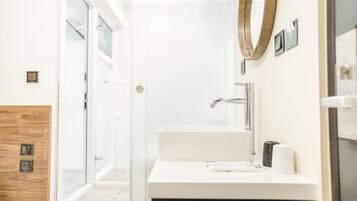 A modern bathroom with a glass shower door, a white sink, and a wooden accent wall.