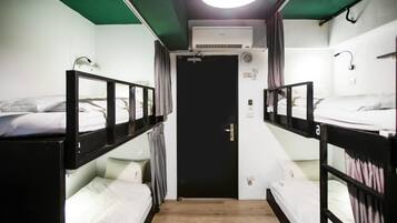 Un pasillo estrecho con literas a ambos lados, una puerta al final y una lámpara en el techo.