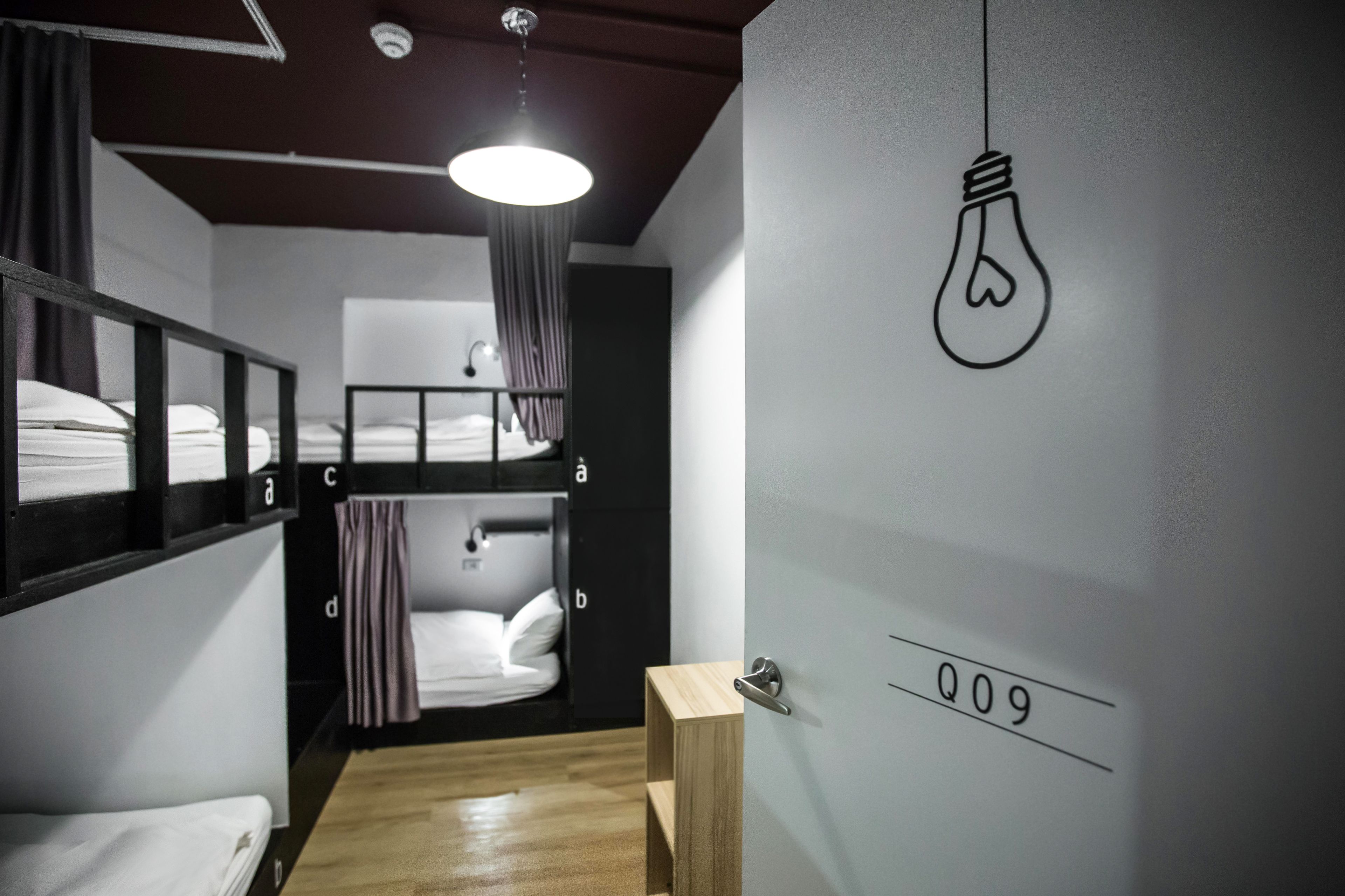 A dormitory room with bunk beds, a wooden door with a number, and a light bulb drawing on the wall.