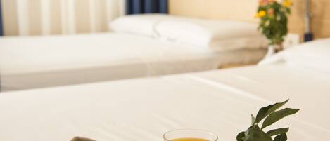 Een ontbijfwagen met croissants, sinaasappelsap en een kopje op een bed in een hotelkamer.