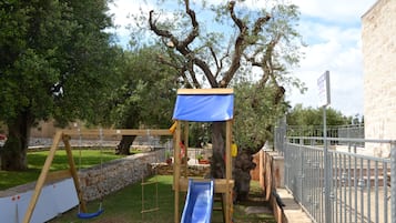 Un parque infantil con tobogán, columpios y estructura para escalar.