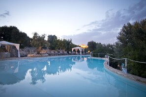 Una piscina con sillones de descanso y un pabellón.
