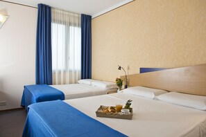 Two single beds with blue bedspreads, a wooden headboard, and a small table with a breakfast tray.