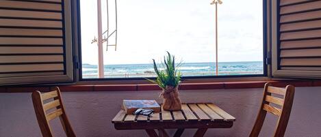 A room with a wooden table and two chairs, a plant, and a book.