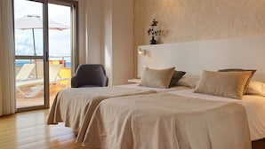 Habitación de hotel con dos camas, una silla, vista al mar y una pared de madera con textura.