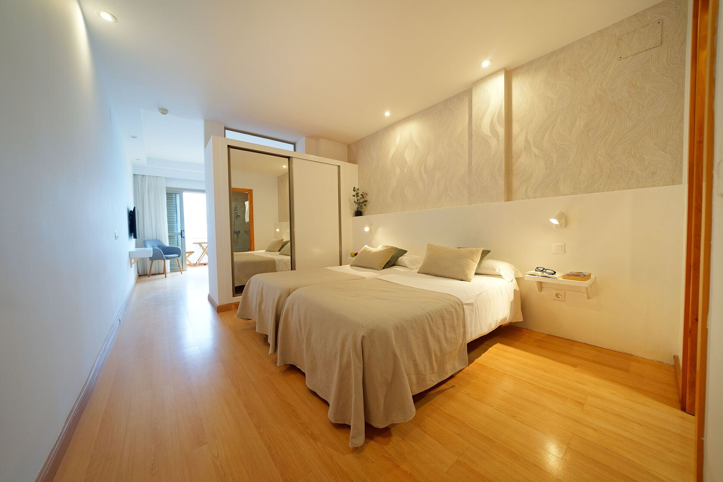 A modern bedroom with a large bed, bedside tables, and a view of a dining area.