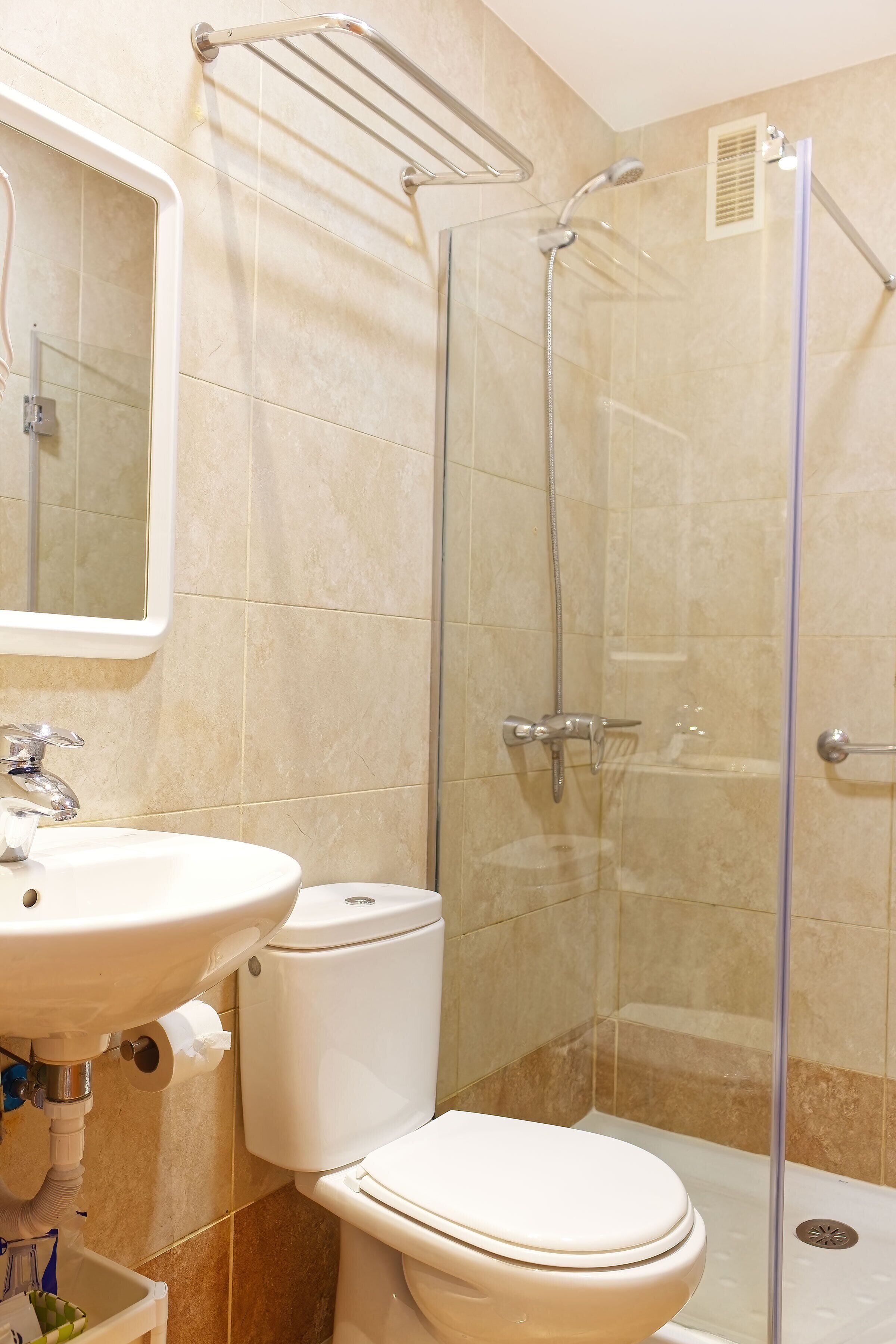 Une salle de bain équipée d’un lavabo, de toilettes et d’une cabine de douche en verre.