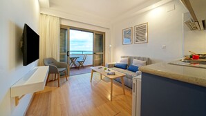 Una sala moderna con televisor de pantalla plana, un sofá, una mesa de centro y un comedor con mesa y sillas.