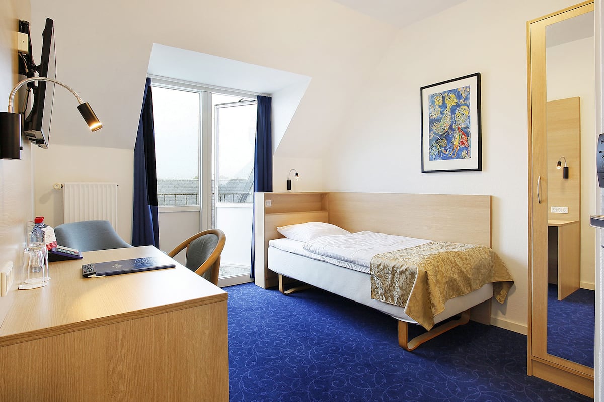 Hotellihuone, jossa on sänky, työpöytä, tuoli ja suuri ikkuna.