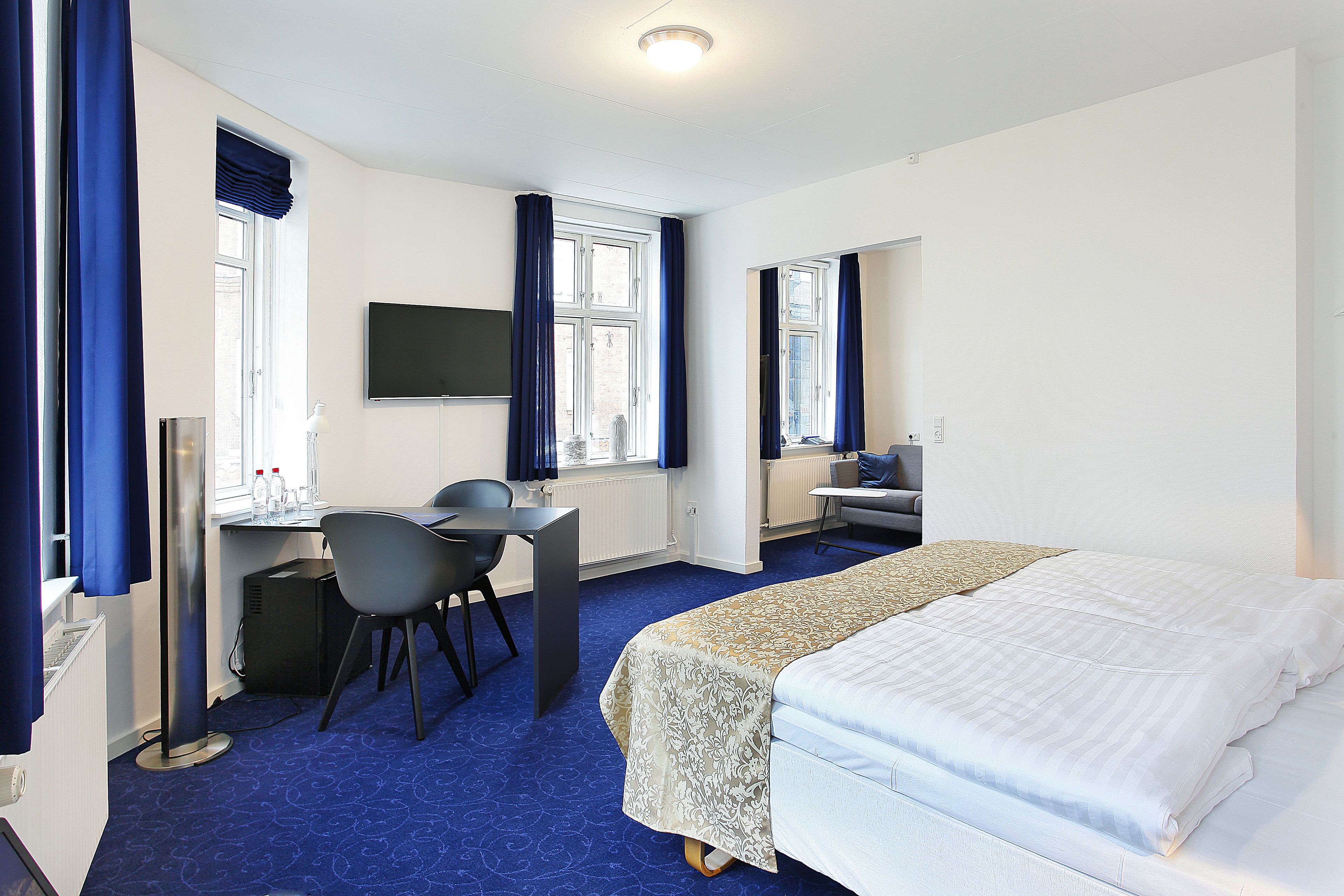 Een hotelkamer met een bed, bureau, stoel en televisie.
