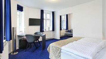 Een hotelkamer met een bed, bureau, stoel en televisie.