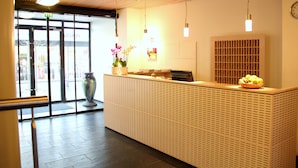 Ein Empfangsschalter mit einem gemusterten Design, eine große Vase mit Blumen und eine Uhr an der Wand.
