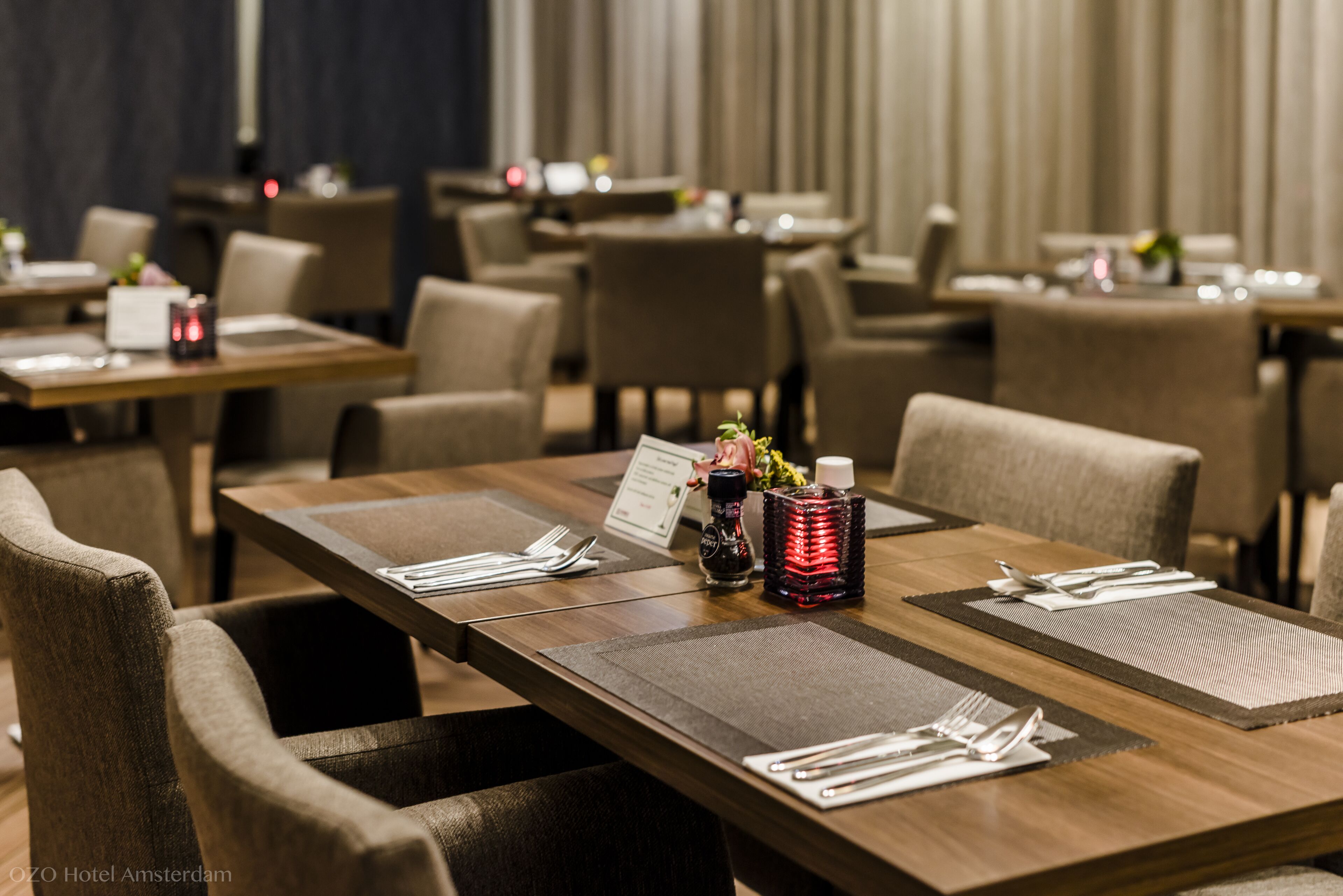 A hotel dining area with multiple tables, each set with white tableware and a menu stand.
