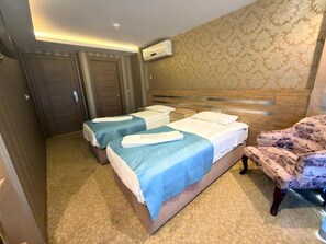 A hotel room with two beds, a patterned wall, and a patterned armchair. - Golden Rain Hotel Old City (Istanbul)