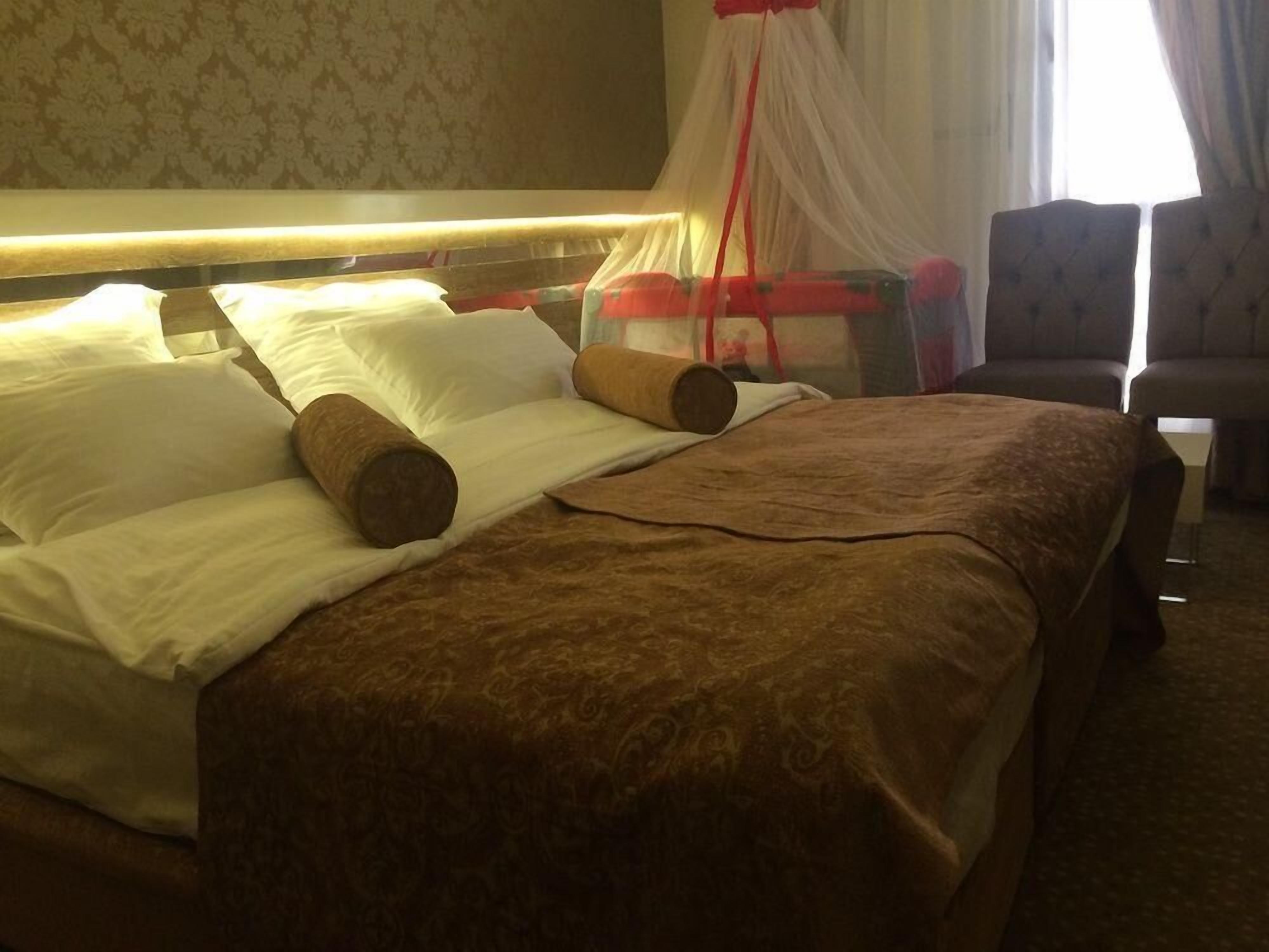 A hotel room with a bed, pillows, a canopy, and a chair.