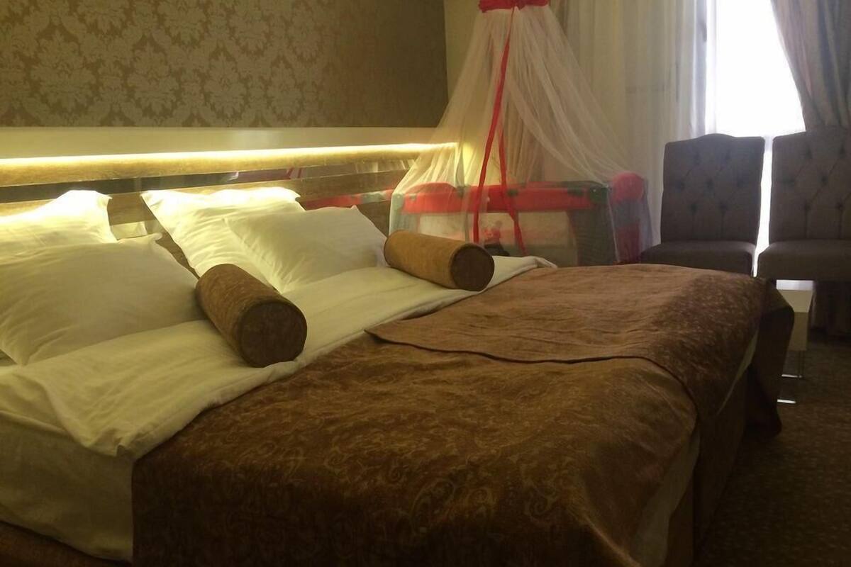 A hotel room with a bed, pillows, a canopy, and a chair.