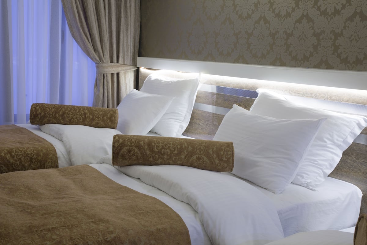 A hotel room with a large bed, two side tables, and a curtain.