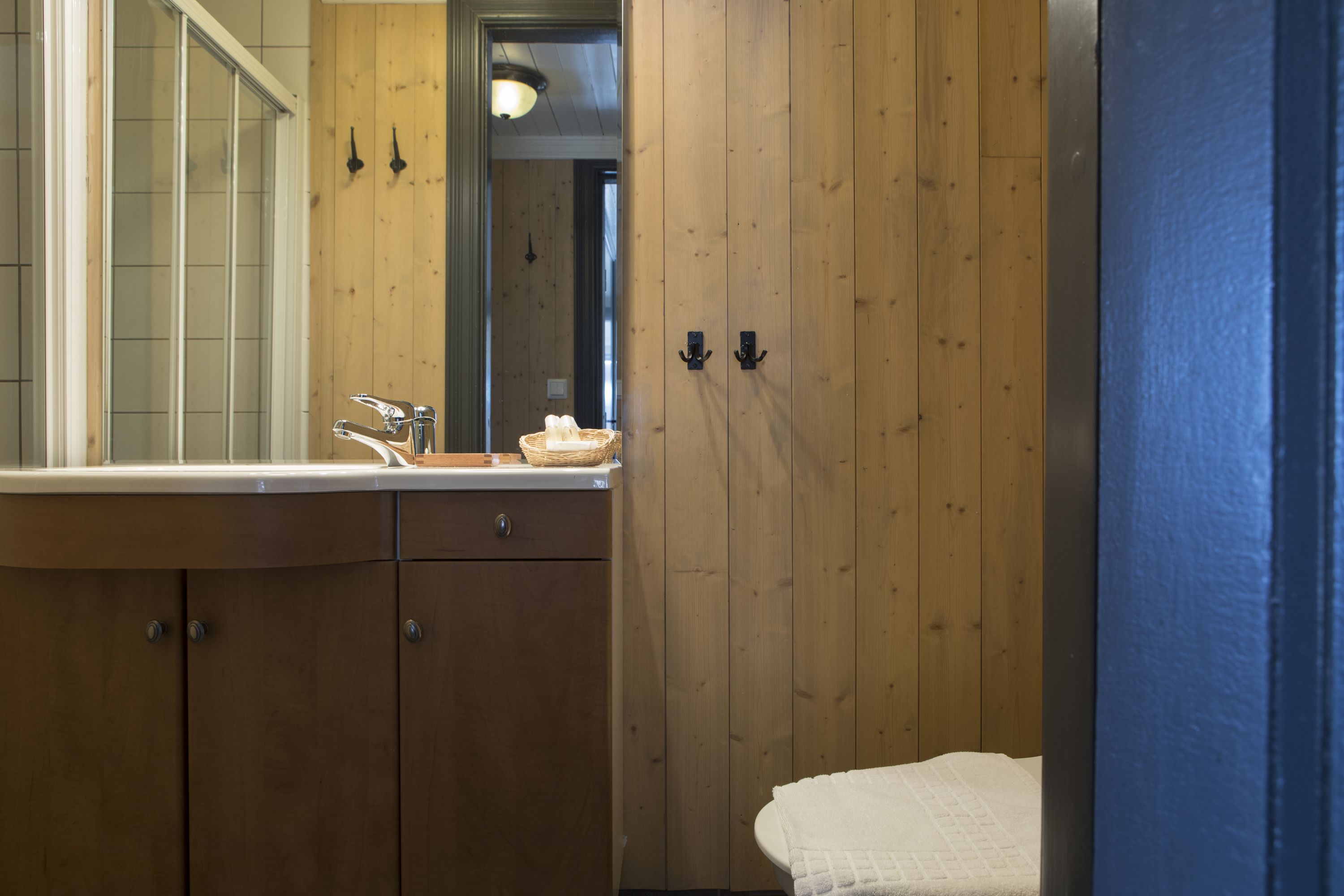 Une salle de bain en bois avec un grand miroir, un lavabo et une serviette accrochée au mur.
