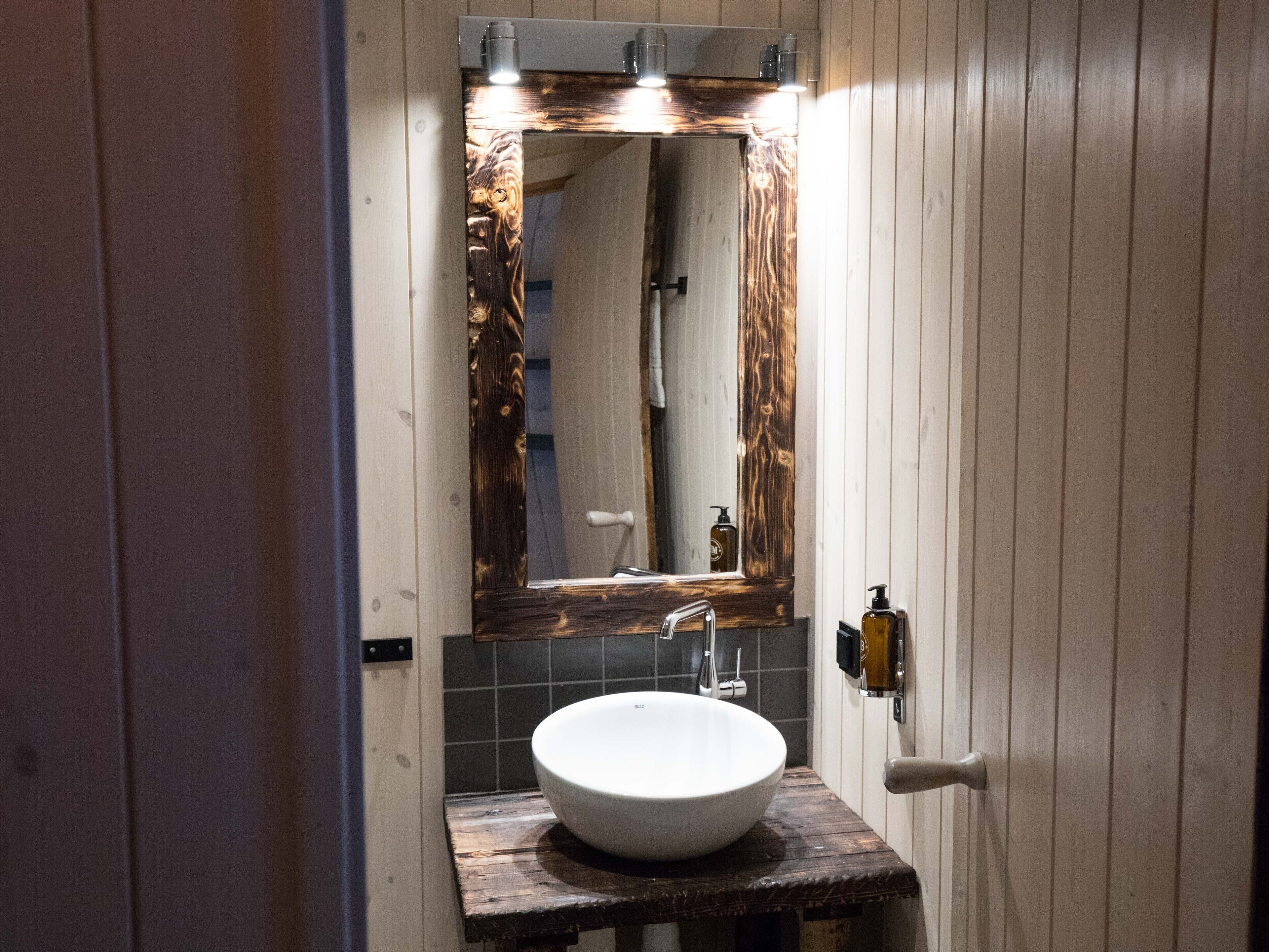 A bathroom with a wooden vanity, a white sink, and a mirror with a wooden frame.